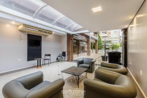Una sala de estar con sofás y sillas y un televisor. en Estudios at Upper Residence - UPP, en Curitiba