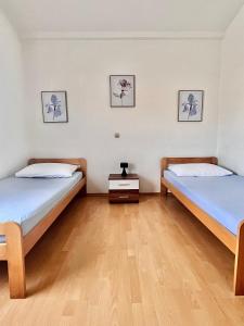 two beds in a room with wooden floors and paintings at Apartmani Fani in Banjol +17 photos