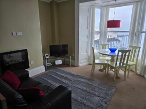 un soggiorno con un divano, un tavolo e una televisione di Seaview Apartment ad Aberystwyth