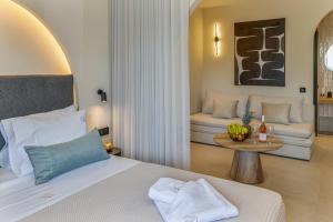 a bedroom with a bed and a table with a couch at Karteris Luxury Suites in Stalida