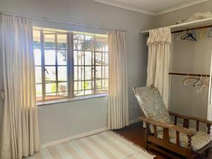 Victorian style cottage in Nyanga - 2096 في Juliasdale: غرفة معيشة مع كرسي ونافذة
