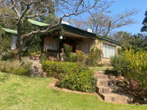 Victorian style cottage in Nyanga - 2096 في Juliasdale: منزل حجري قديم به شجرة وبعض الشجيرات