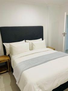 a large white bed with a black headboard and white pillows at Canvas Lofts 1 – Famona modern 2-bed - 2310 in Bulawayo