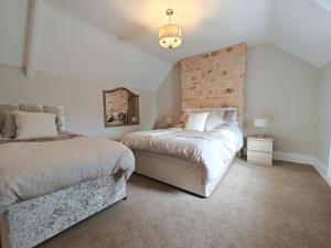 a bedroom with two beds and a brick wall at 3 Bed in Mealsgate oc-e33626 in Mealsgate