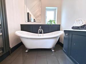 a white bath tub in a bathroom with a mirror at 3 Bed in Mealsgate oc-e33626 in Mealsgate +11 photos