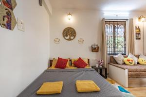 a bedroom with a bed with yellow pillows and a couch at Ground Floor Studio With S Pool 3 Min Ride To Benaulim Beach in Benaulim +13 photos