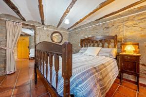 Un dormitorio con una cama de madera en una habitación con paredes de piedra. en Casa Rural Masdenverge, en Masdenverge