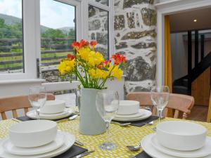 a dining table with a vase of flowers on it at Ysgoldy Salem in Mallwyd +10 photos