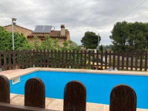 una valla con una piscina azul frente a una casa en Cirerers - Casa Rural, en Masdenverge