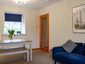 a living room with a blue couch and a window at Airdside Cottage in Crossmichael
