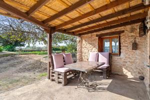 un patio con mesa y sillas bajo un techo de madera en Cirerers - Casa Rural, en Masdenverge