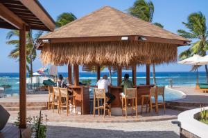 people sitting at a bar with the ocean in the background at Naya Lodge in Mitsamiouli