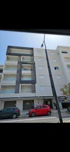 a red car parked in front of a building at Appartement Cocooning de Sousse in Hammam Sousse