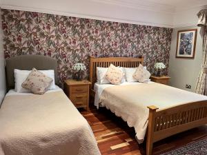 deux lits dans une chambre avec papier peint fleuri dans l'établissement Acorn Guest House in Hull, à Hull