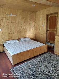 a bedroom with a bed in a wooden room at Shugu a village home stay in Gondla