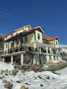 a house on a hill with snow in front of it at Shugu a village home stay in Gondla