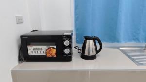 a microwave sitting on a counter next to a coffee pot at Keerana Villa in Uttaradit