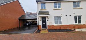 een wit huis met een auto geparkeerd op de oprit bij Solid Mirror Home Milton Keynes in Bletchley