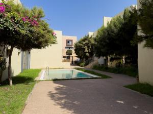a swimming pool in a yard with trees and a building at Ocean Escape Luxury Duplex With Sea View & Pool in Tamraght Ouzdar