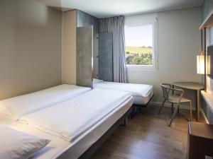 a hotel room with two beds and a window at ibis budget Fribourg in Fribourg