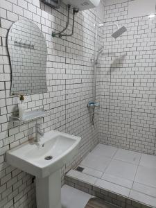 にあるAdelpha Properties,Abelenkpe accraの洗面台とシャワー付きの白いバスルーム +1枚の写真