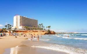 a beach with people in the water and a building at Casa iris in San Miguel de Salinas