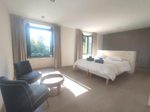 a bedroom with a bed and a chair and a table at Séjour d'exception au Moulin de la Vernède avec piscine, ruisseau, climatisation et parking in Conques-sur-Orbiel +30 photos