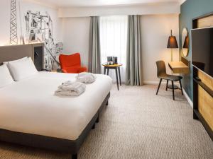 a hotel room with a bed and a desk at Mercure Cardiff in Cardiff