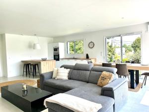 a living room with a gray couch and a kitchen at La Rose, au calme aux portes de Limoges in Feytiat