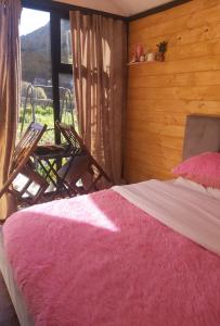 a bedroom with a bed and a chair and a window at Boga Cabins in Bogë