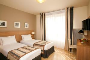 a hotel room with two beds and a window at Séjours & Affaires Paris-Vitry in Vitry-sur-Seine