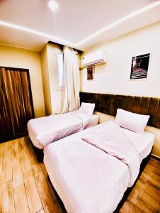 two beds in a hotel room with white sheets at AB pyramids view in Cairo +21 photos