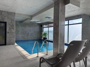 a pool with two chairs and a swimming pool with windows at Lavalliere Hotel & Villas in Sarnitsa