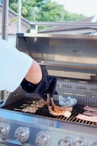 a person is cooking food on a grill at 大洗の眺望抜群なコンテナハウス #一棟貸切 #本格BBQ #大型ガスグリル完備 #大洗 #OURoom1st in Oarai