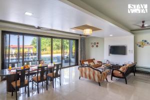 a living room with a table and chairs and a television at StayVista at Ocean Breeze with Bonfire & Pool in Guhagar