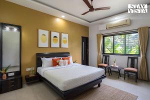 a bedroom with a bed and a ceiling fan at StayVista at Ocean Breeze with Bonfire & Pool in Guhagar