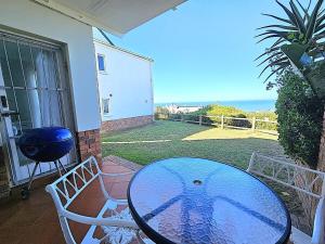 a table and chairs on a patio with a view of the ocean at Dolphin Nook 29 in Gqeberha