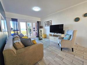 a living room with a couch and a flat screen tv at Dolphin Nook 29 in Gqeberha