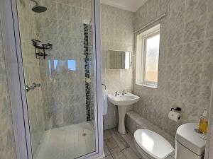 a bathroom with a shower and a toilet and a sink at Dolphin Nook 29 in Gqeberha +17 photos