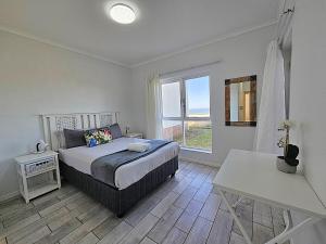 a bedroom with a bed and a large window at Dolphin Nook 29 in Gqeberha