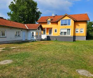 une maison jaune avec une cour devant elle dans l'établissement Idyllisches Ferienhaus Parndorf, à Parndorf
