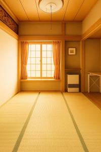 白馬村にあるDeep Powder Lodge HAKUBAの大きな窓とラグが備わる空の部屋 +6枚の写真