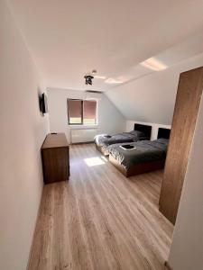 a bedroom with two beds and a wooden floor at La Izvor Moinești, Cazare in Moineşti