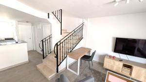 Una sala de estar con una escalera y una mesa y un televisor. en Casa Isabel in El Verger, en El Verger
