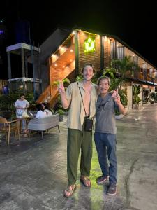 two men standing in front of a building with their hands up at U OLIVE Hotel in Ban Nua