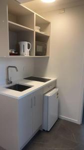 a white kitchen with a sink and a refrigerator at Pure Motel in Rotorua