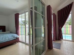 a bedroom with a glass door with a bed and windows at บ้านสวนแสงหล้า วิลล่า รีสอร์ท 