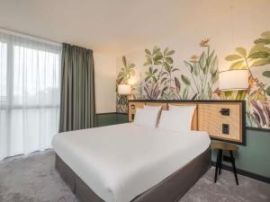 a large white bed in a room with a mural at Mercure Le Mans Batignolles - Hotel & Spa in Le Mans