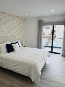 a white bedroom with a large white bed with blue pillows at Bella Casa Bed and Breakfast in Ponta Delgada