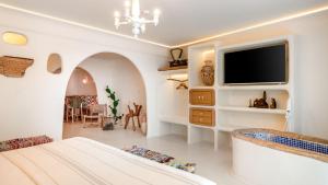a white bedroom with a tv on a wall at Glam Taoo Hotel Apartamento Boutique in Lugo